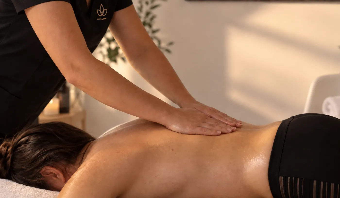 Des mains massent le dos d’une personne allongée sur la table de soin